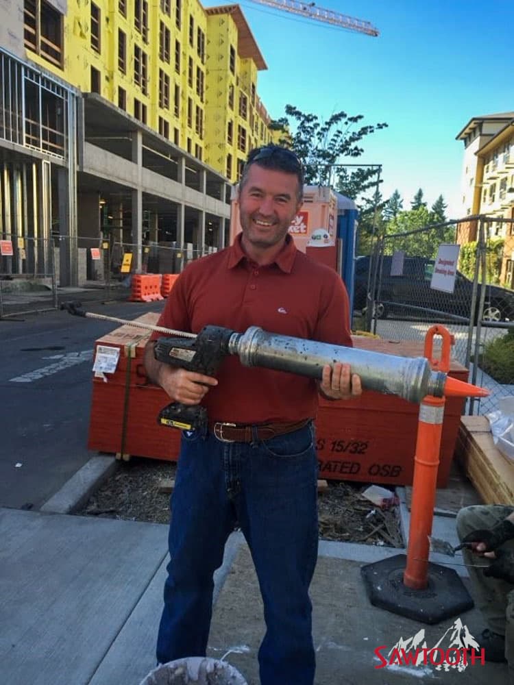 Tyler Stoller on a job site holding a bulk caulking gun